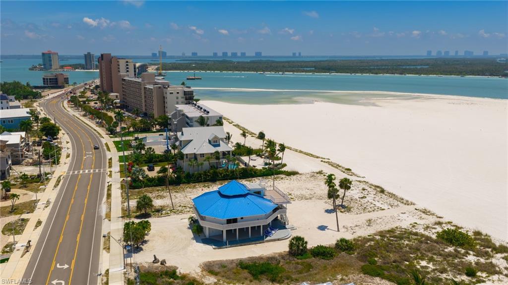 Coastal property featuring a unique octagonal structure with a blue roof, white exterior, and elevated foundation - Virtually Edited Image