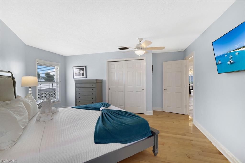 Bedroom featuring wood-finish flooring, light blue walls, and white trim - Virtually Edited Image