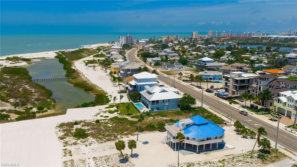 Coastal property with direct beach frontage and Gulf of Mexico access, featuring a light blue exterior, multiple balconies, and a metal roof - Virtually Edited Image