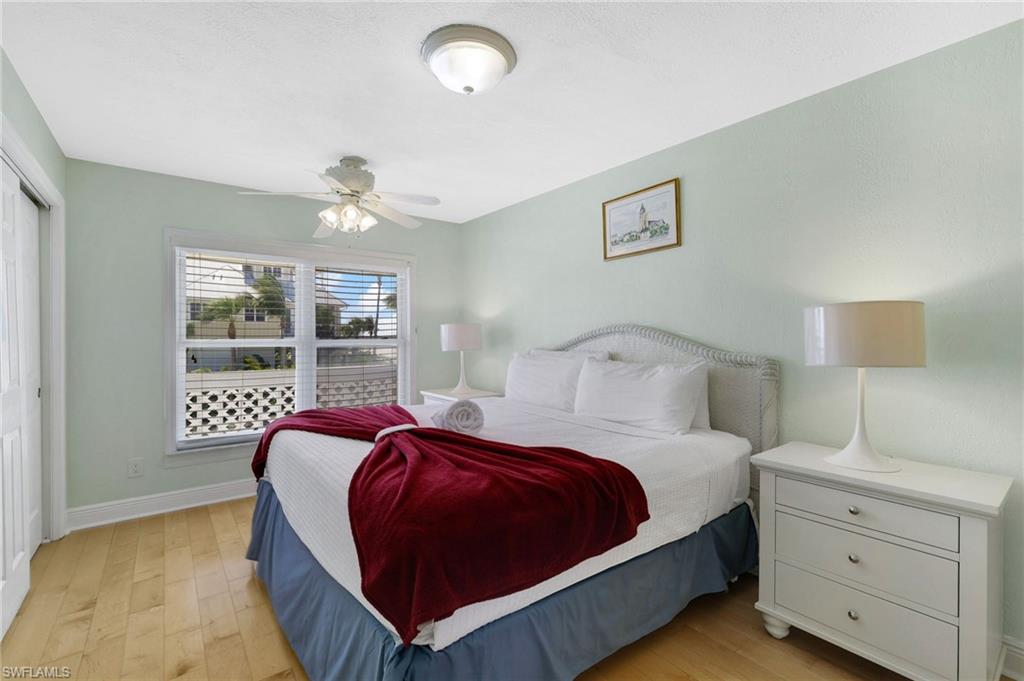 Room featuring wood-finish flooring, a window with horizontal blinds, and a ceiling fan with integrated lighting - Virtually Edited Image