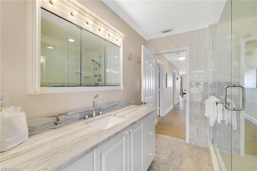 Bathroom featuring a spacious vanity with a stone countertop, built-in sink, and polished chrome faucet - Virtually Edited Image