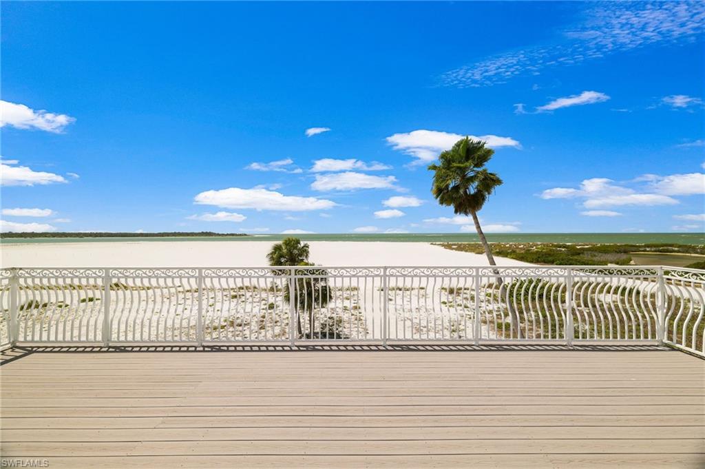 Expansive outdoor decking featuring a decorative white metal railing, beachfront setting, and distant water - Virtually Edited Image