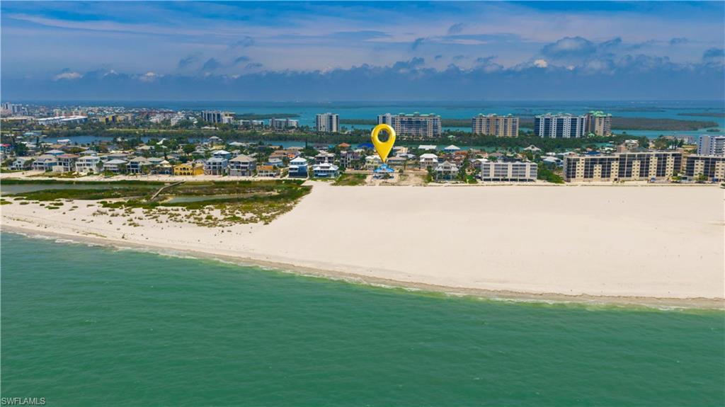 Aerial coastal landscape featuring a broad sandy beach, turquoise waters, and distant high-rise buildings - Virtually Edited Image