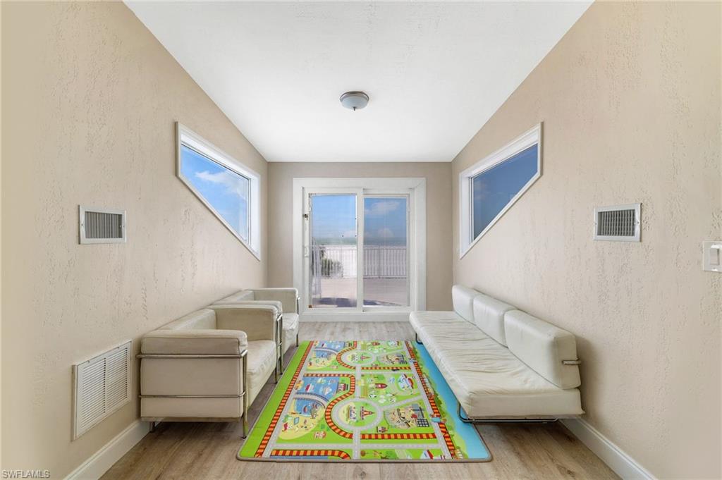 Room with two unique triangular windows and a sliding glass door leading to an outdoor deck - Virtually Edited Image
