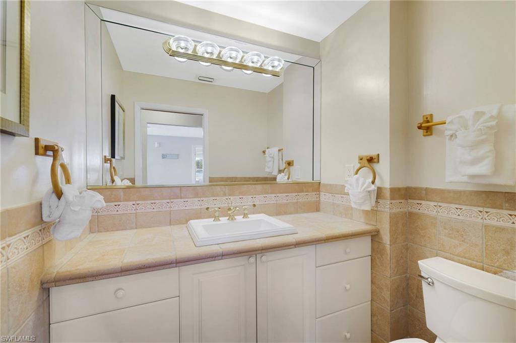 Bathroom vanity featuring a single basin, brass-finish faucet, and substantial mirror - Virtually Edited Image