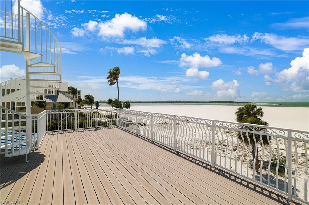 Spacious outdoor deck with composite wood-finish flooring, white decorative railings, and a spiral staircase - Virtually Edited Image