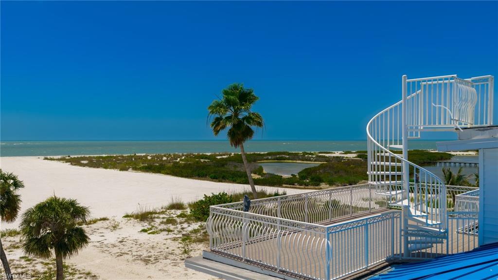 Rooftop deck featuring a white spiral staircase, white railing, and coastal scenery with a sandy beach and ocean - Virtually Edited Image