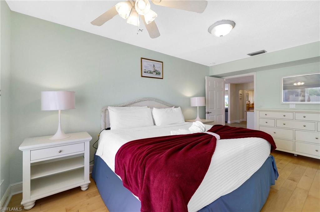 Spacious room featuring wood-finish flooring, light green walls, a white ceiling fan, and recessed lighting - Virtually Edited Image