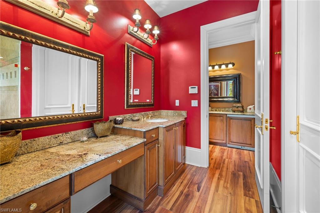Vanity area featuring wood-finish flooring, granite countertops, and rich wood cabinetry