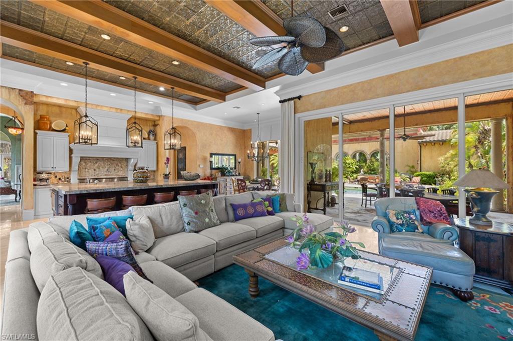 Expansive living area with a coffered ceiling featuring wood beams and a decorative ceiling fan