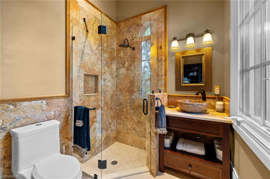 Frameless glass shower enclosure featuring natural stone tiling and a built-in niche