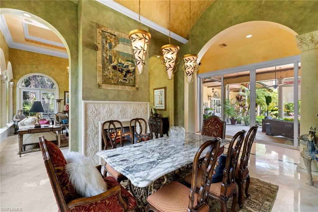 Dining area featuring a marble-topped table, decorative fireplace with an ornate mantel, and three pendant light fixtures