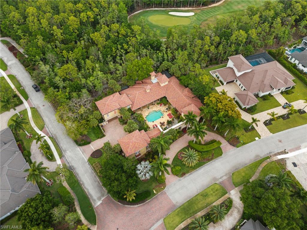 Mediterranean-style property featuring a central courtyard with a swimming pool, a red tile roof, and a meticulously landscaped circular driveway
