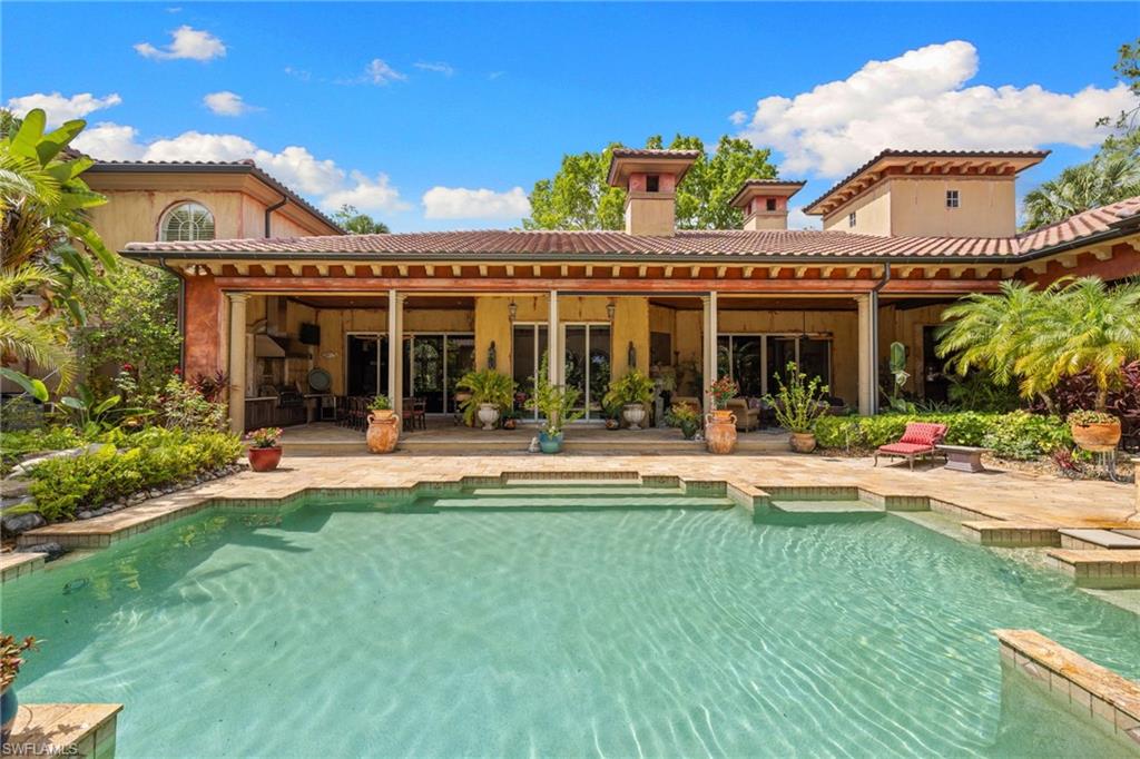Mediterranean-style residence featuring a structured swimming pool with integrated steps, a spacious covered patio, and terracotta roof tiles