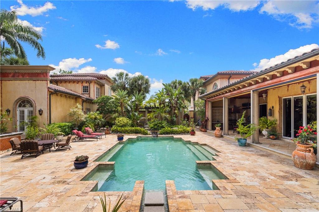 Courtyard-style pool area featuring a rectangular pool with integrated steps, surrounded by stone pavers