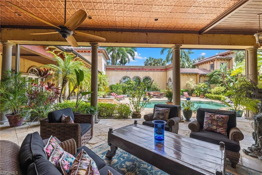 Covered patio featuring a wood-finish ceiling fan, stone-finish columns, and a textured ceiling