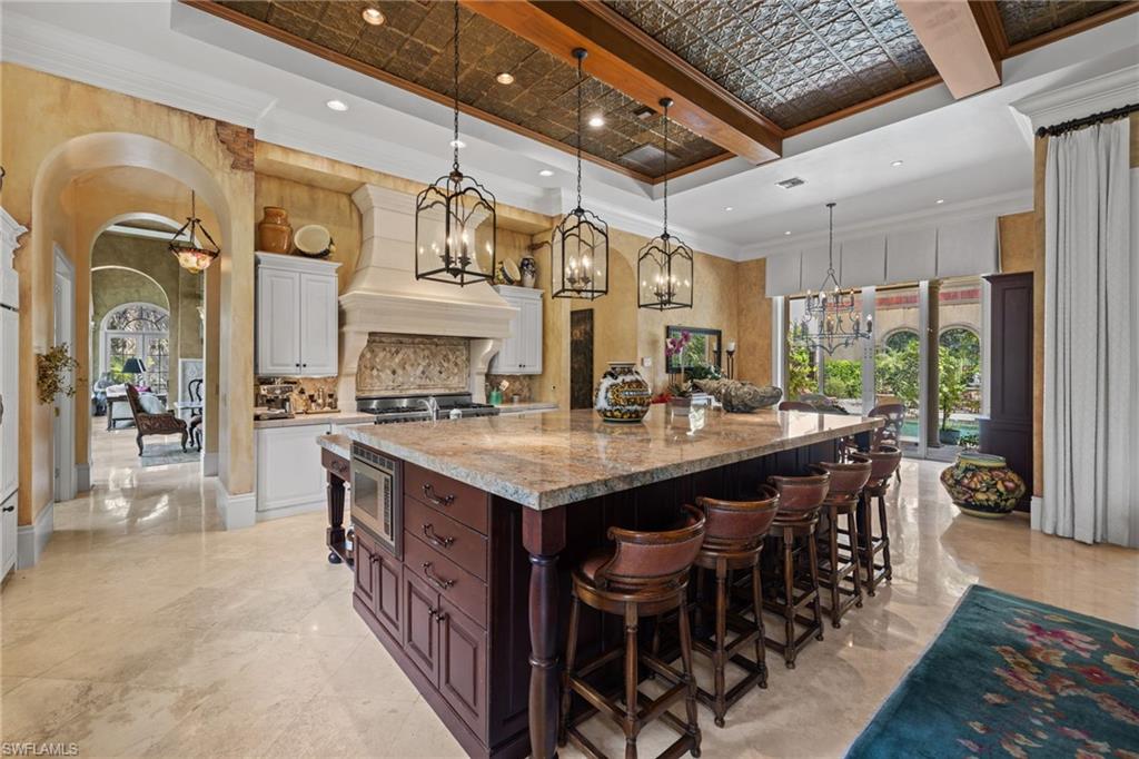Gourmet kitchen featuring a large island with integrated microwave, stone countertops, and dark wood cabinetry