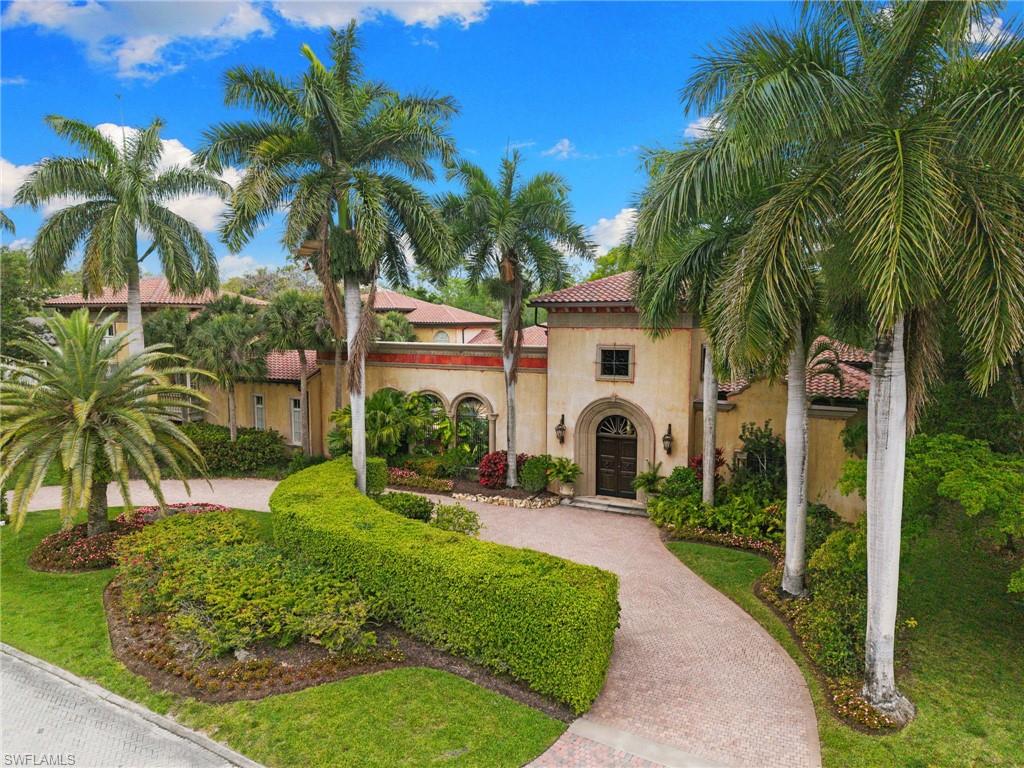 Mediterranean-style facade featuring an arched entryway with a solid wood door, clay tile roof, and stucco exterior