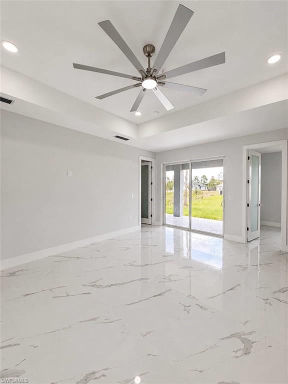 Spacious interior featuring a contemporary ceiling fan with integrated lighting, recessed ceiling lights, and tray ceiling detailing