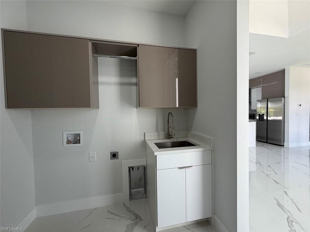 Dedicated laundry space featuring a utility sink, wall-mounted cabinetry, and a chrome faucet