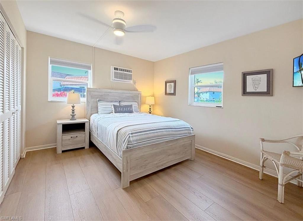 Bedroom with ceiling fan, a closet, multiple windows, and light wood-type flooring