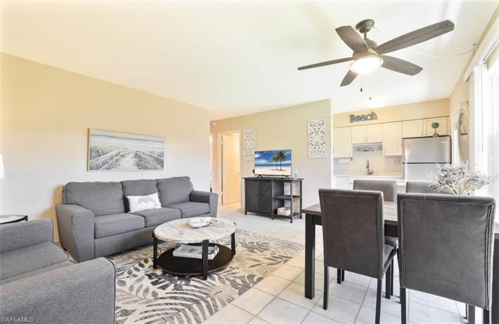 Living area with light tile patterned floors and a ceiling fan.