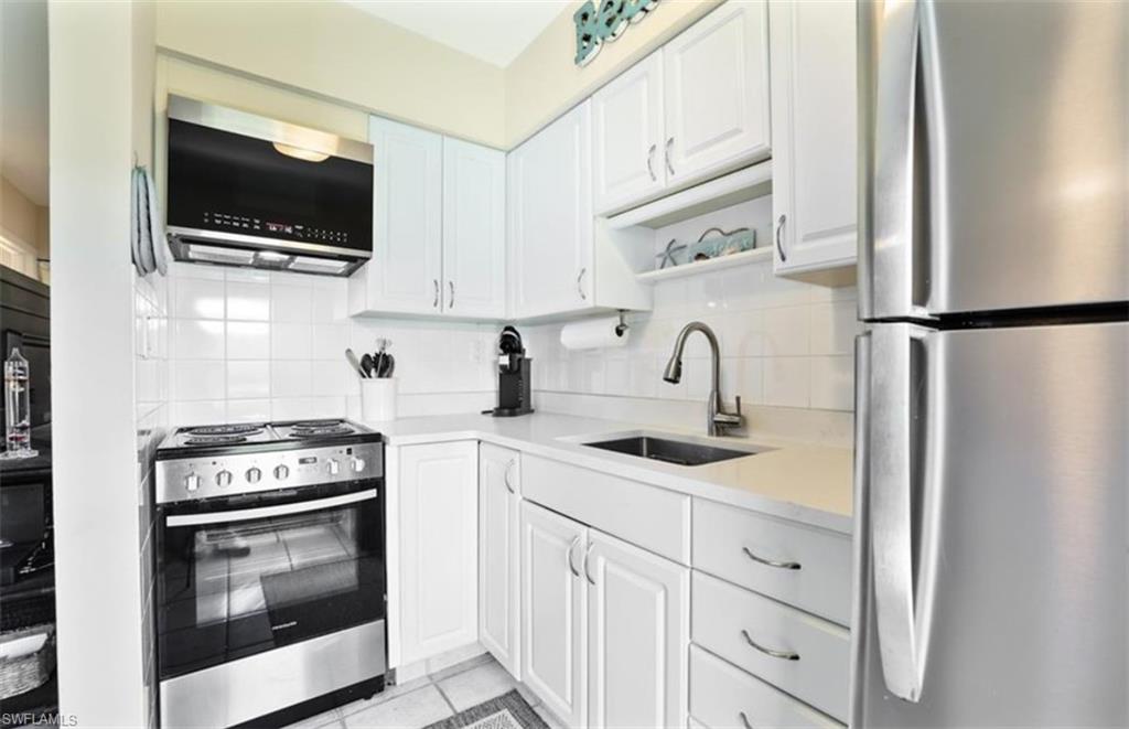 Kitchen with a sink, light countertops, decorative backsplash, ad appliances with stainless steel finishes.