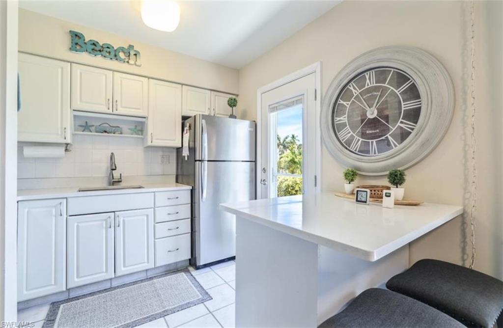 Kitchen with a sink, freestanding refrigerator , white cabinetry, tasteful backsplash, and a peninsula.