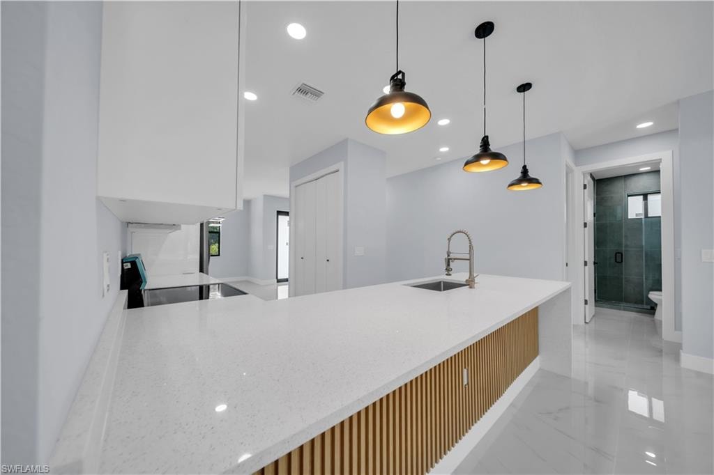 Kitchen island featuring a white speckled countertop, integrated sink, and wood-slat accent paneling