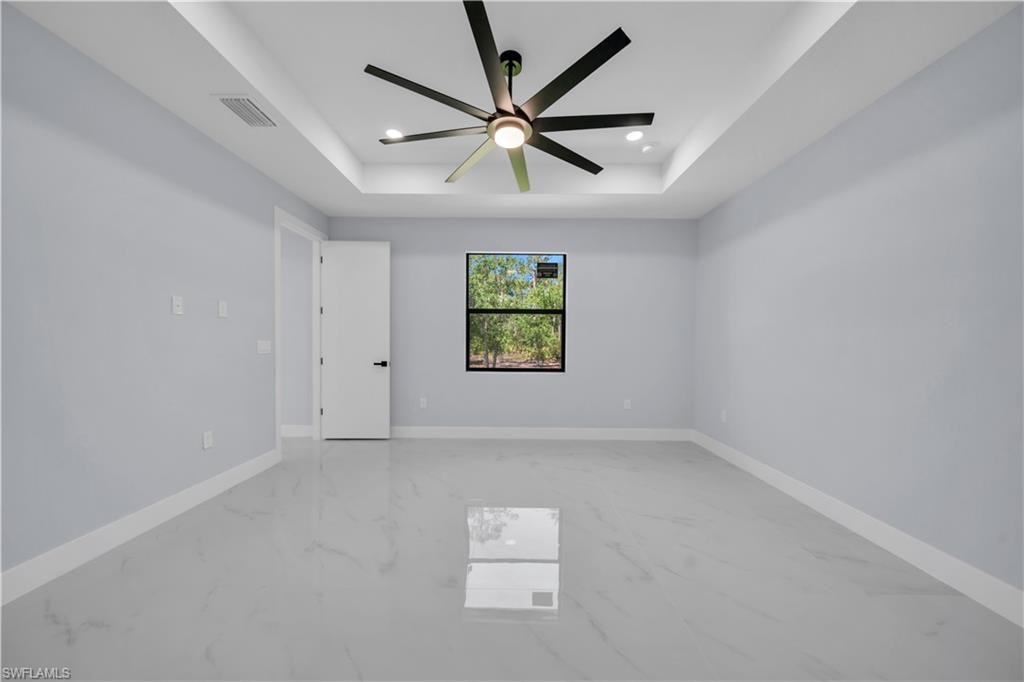 Recessed tray ceiling with a modern ceiling fan, light gray walls, and large format tile flooring