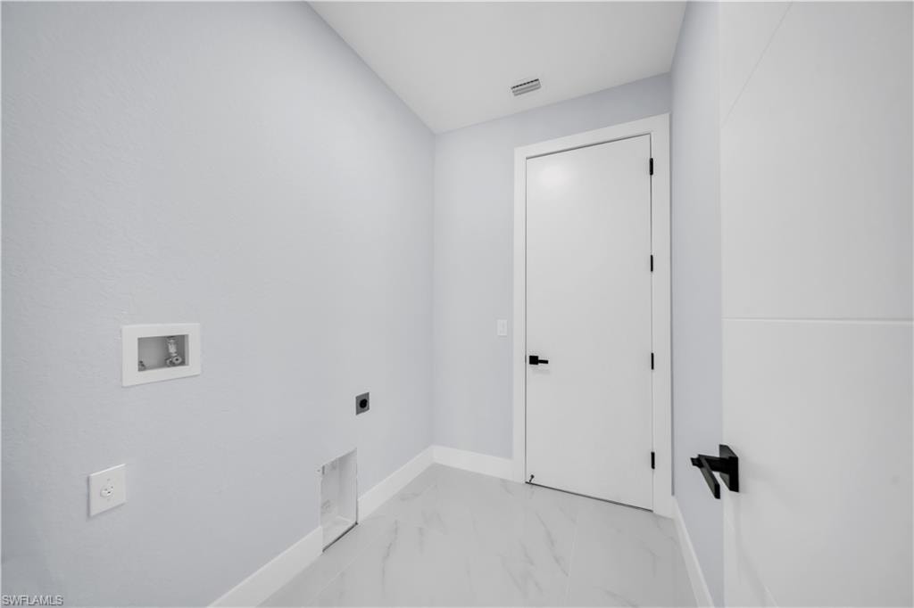 Dedicated utility area featuring connections for laundry appliances, light gray wall paint, white baseboards, and a white door with a black handle