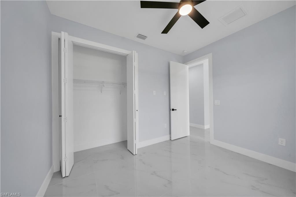 Room featuring light gray walls, white trim, and a ceiling fan with integrated lighting