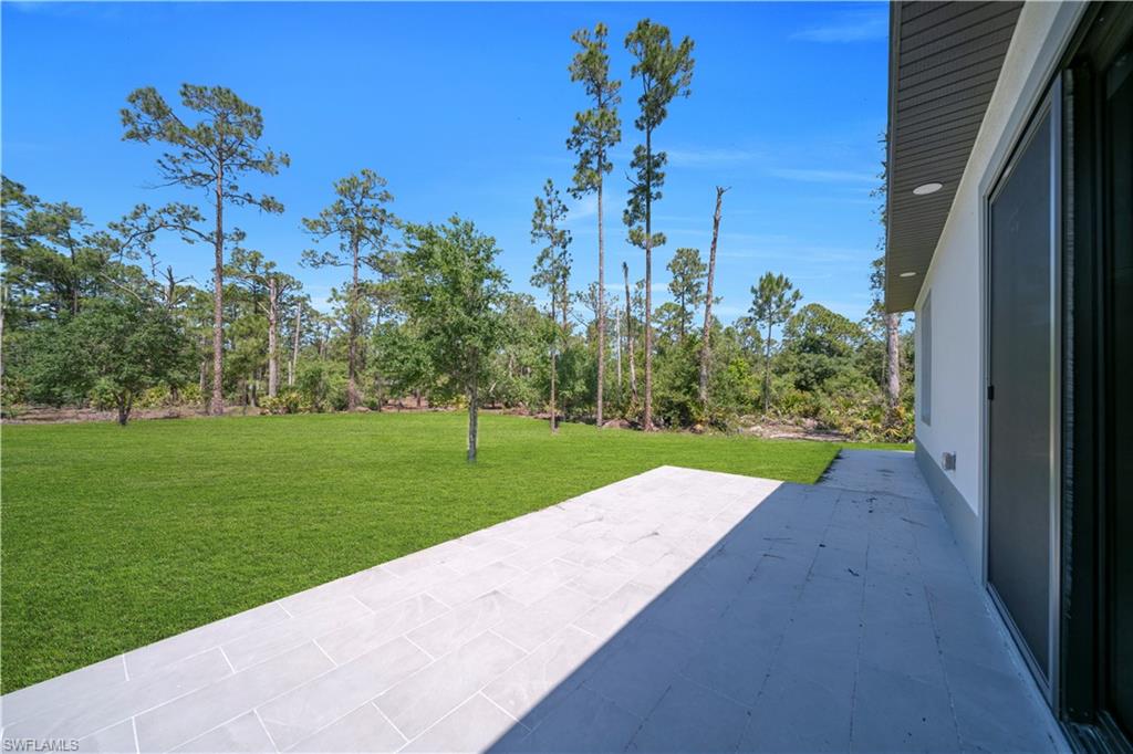 Expansive green lawn with mature trees and a paved patio area