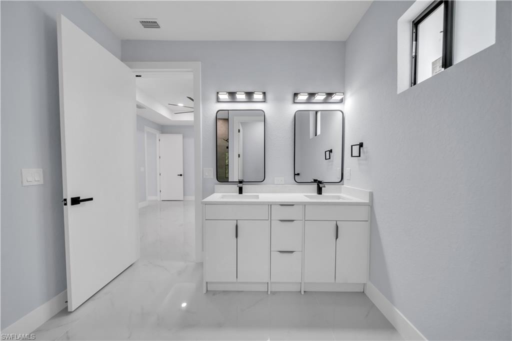 Dual vanity with white cabinetry, integrated sinks, black framed mirrors, and contemporary wall sconces
