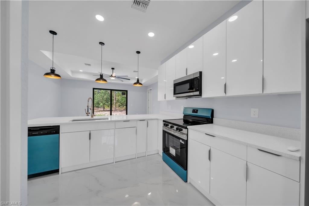 Modern kitchen featuring white high-gloss cabinetry, light-toned countertops, and a full suite of appliances including a range, microwave, and dishwasher