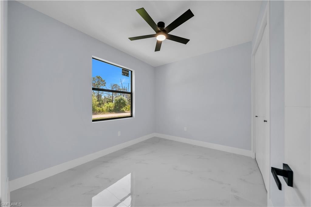 Bright room featuring a single window, a contemporary ceiling fan, and light-toned flooring