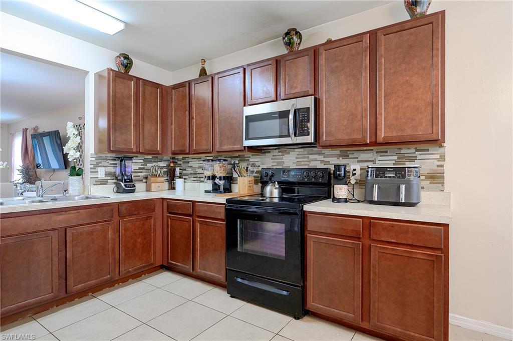 Kitchen featuring wood-finish cabinetry, light-toned countertops, and a full-height mosaic tile backsplash
