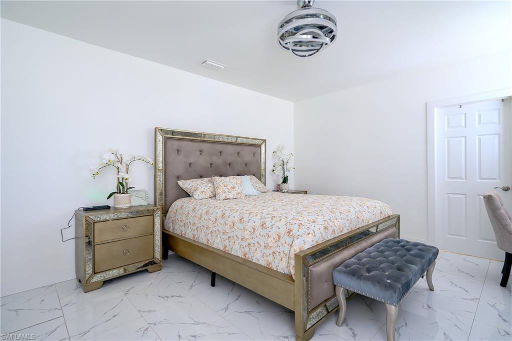 Spacious interior room featuring white walls, large format tile flooring with subtle veining, and a flush-mount light fixture