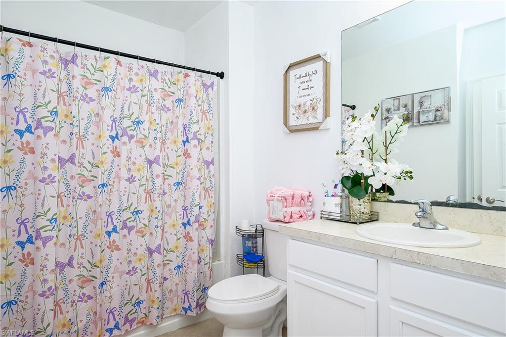 Bathroom featuring a white vanity with panel cabinetry, a light-colored countertop, and an integrated sink with a chrome faucet