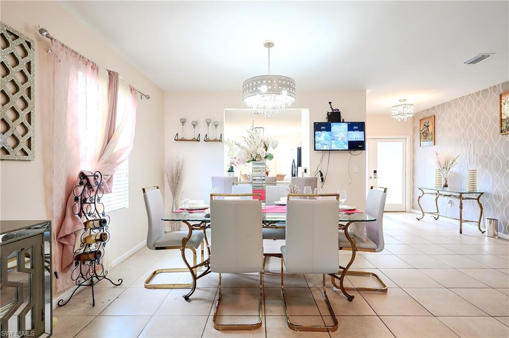 Dining area featuring a central chandelier, tiled flooring, and accent wall with patterned wallpaper