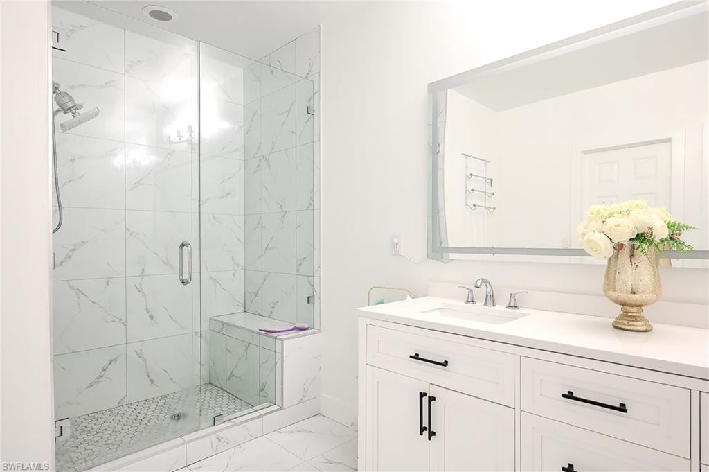 Spacious bathroom featuring a glass-enclosed shower with a built-in bench, marble-patterned tile, and a hex-tile shower floor