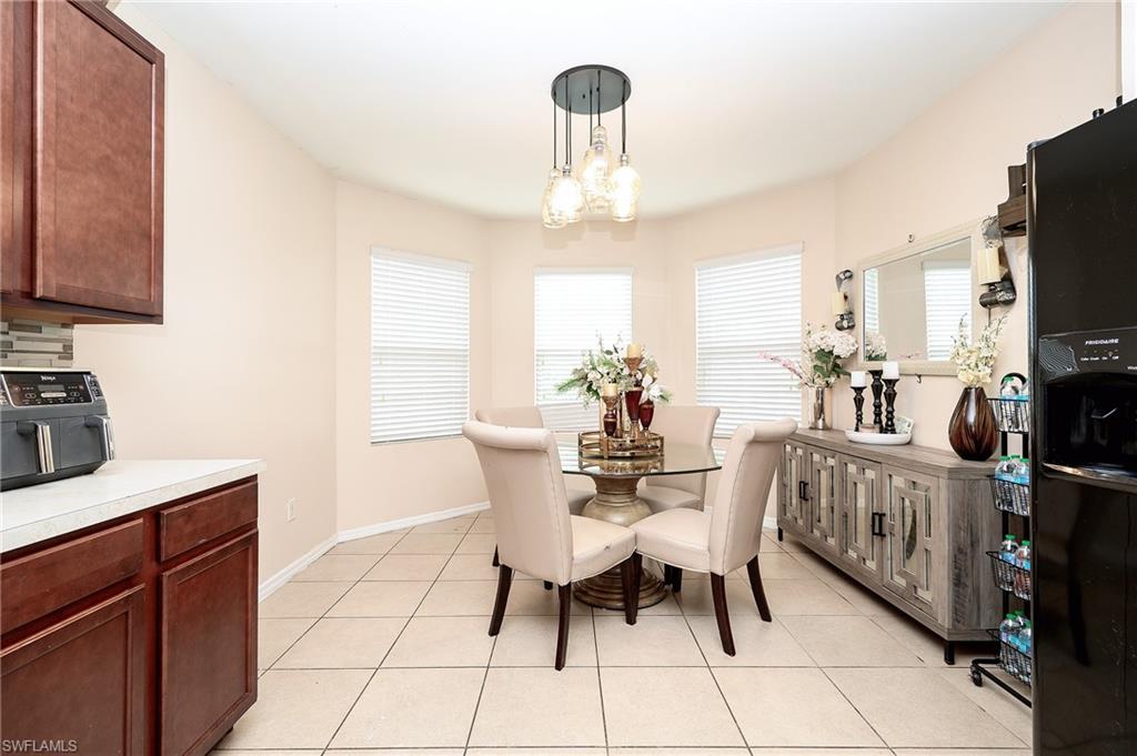 Open-concept dining area featuring a three-light pendant fixture, three large windows with horizontal blinds, and large format tile flooring