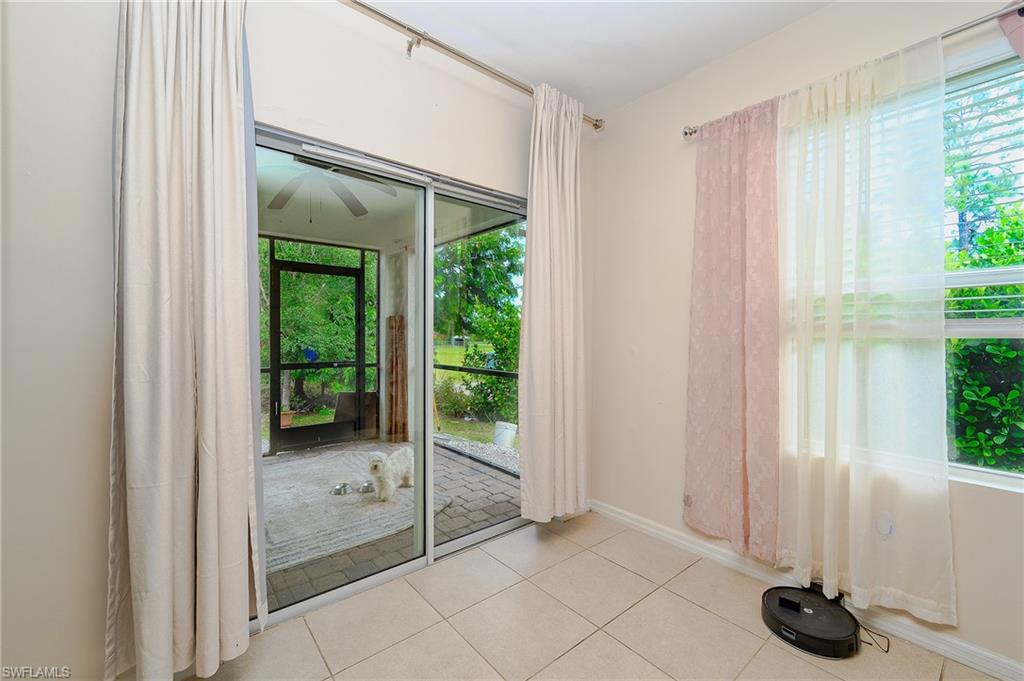 Tiled flooring throughout this room, featuring direct access to a screened patio and a window with horizontal blinds