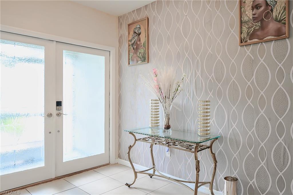 Entryway featuring double French doors with frosted glass panels, a digital smart lock, tiled flooring, and a textured accent wall