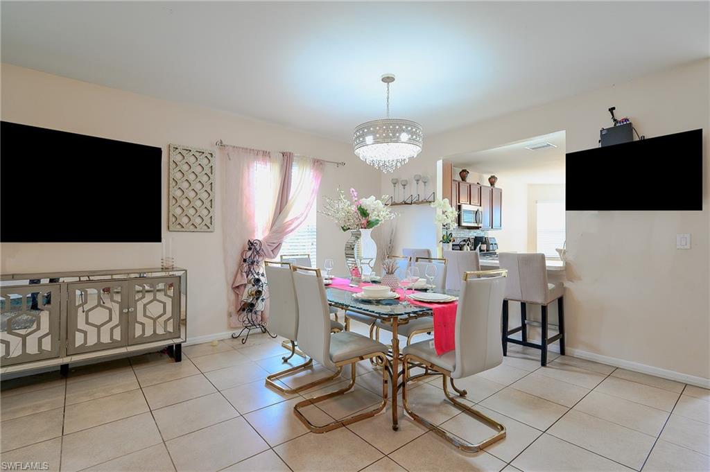 Dining area featuring tile flooring, a decorative chandelier, and a pass-through opening to the kitchen with a breakfast bar