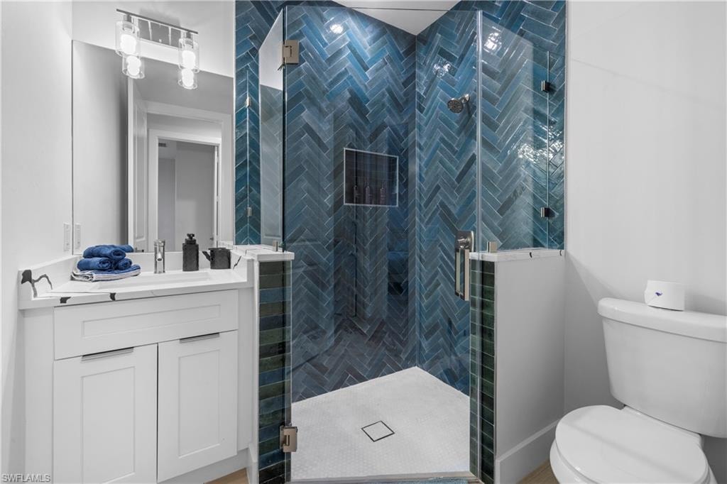 Modern bathroom featuring a glass-enclosed shower with blue herringbone tile, a built-in shower niche, and a white vanity with integrated sink