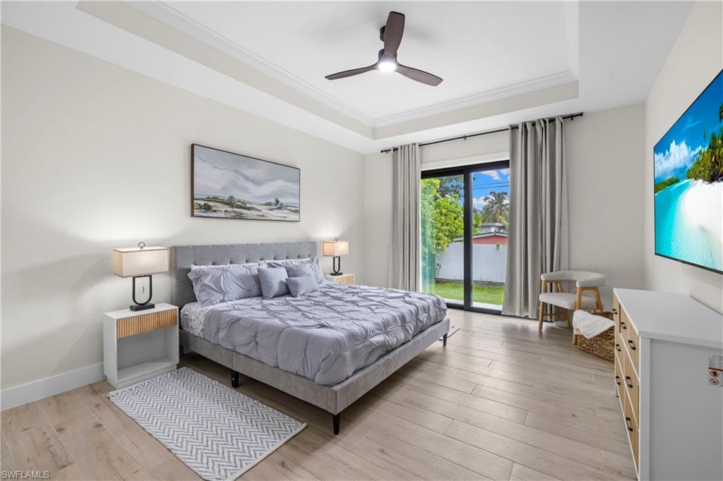 Spacious room featuring wood-finish flooring, a contemporary ceiling fan, and a tray ceiling