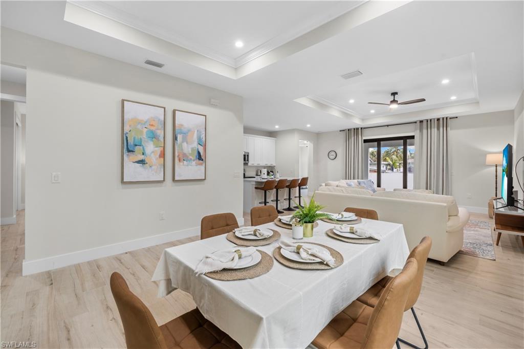 Open-concept living area with tray ceilings and recessed lighting