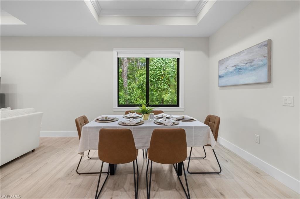 Dining area featuring light wood-finish flooring, a tray ceiling, and a large window with black trim