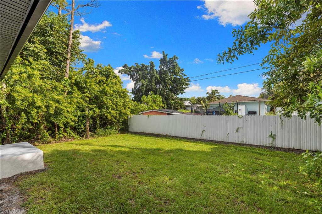 Expansive green lawn framed by a privacy fence and mature trees